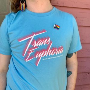 Photo of a person wearing a bright blue t-shirt with pink and white words scrawled across is: Trans Euphoria. Grand Rapids Trans Foundation.