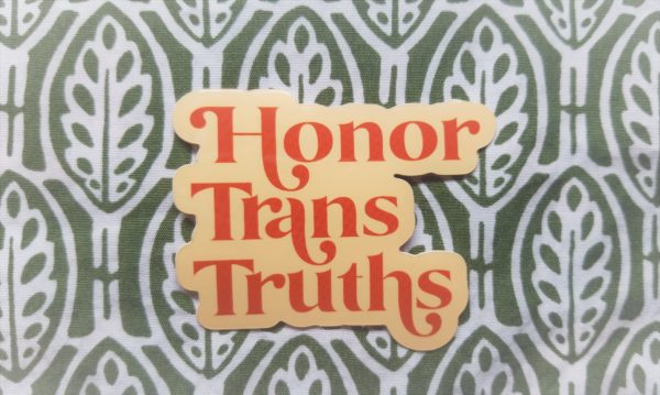 Set against a dark green and white design sits a cream colored vinyl sticker that says Honor Trans Truths in an burnt orange embellished font.